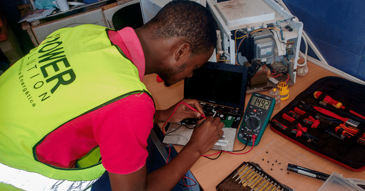 Técnico a reparar um equipamento electrónico com multímetro na bancada